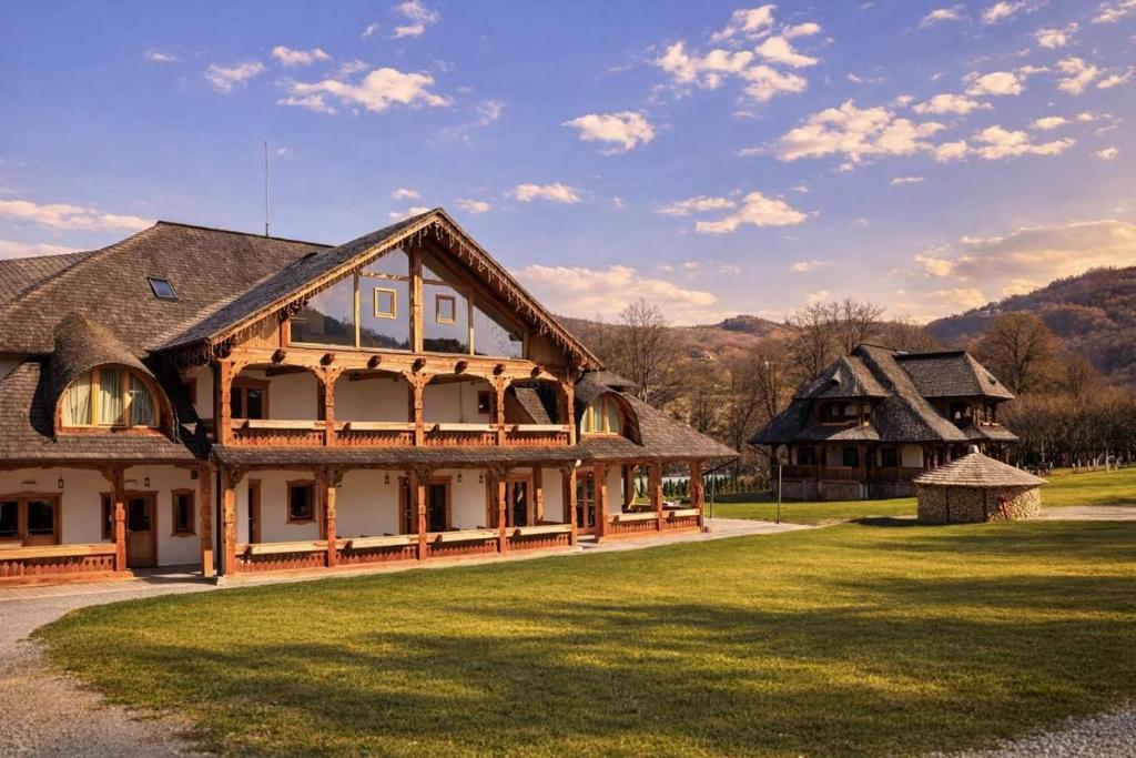 a large house with a grassy yard next to a building at Prispa Premium Resort in Vişeu de Sus