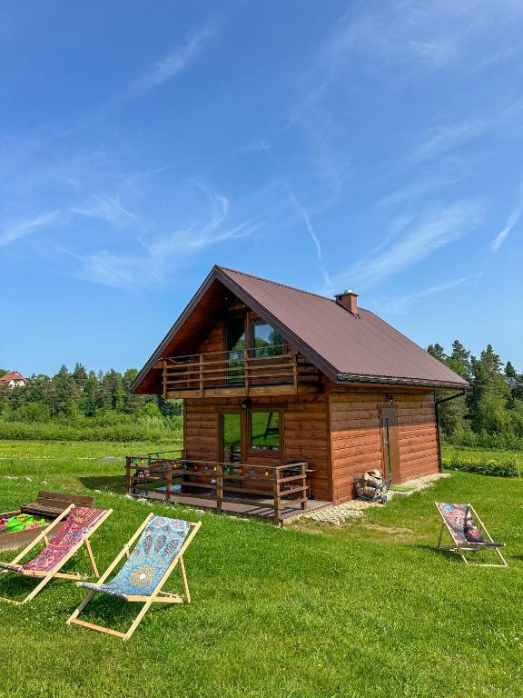 a log cabin with two lawn chairs in front of it at Chatki Bies-Czadowe-Czad in Berezka