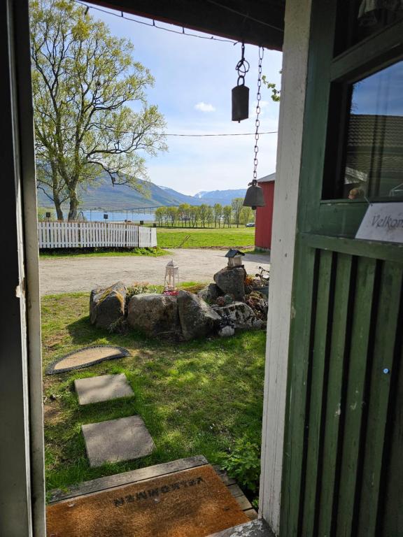 an open door to a yard with a view at Hammergaarden Stabbursstua - Heritage Loft Stay in Sortland