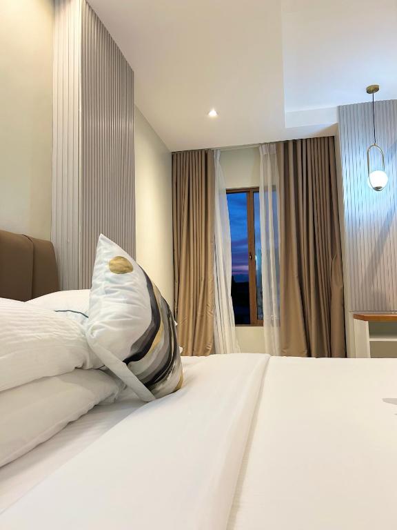 a bedroom with a white bed with a pillow on it at Olive's Suites in Kalibo