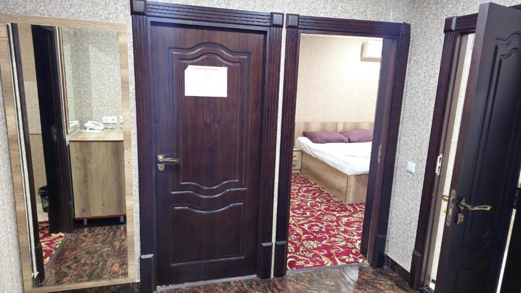 a wooden door in a room with a bed at Sitora in Chirchiq