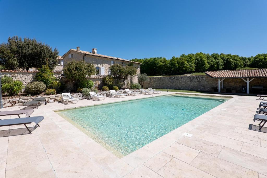 a swimming pool with chairs and a house at La Ferme D'estafinette in Redortiers