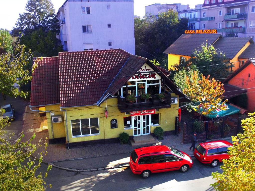 een rode auto geparkeerd voor een geel gebouw bij Casa Belazur in Deva