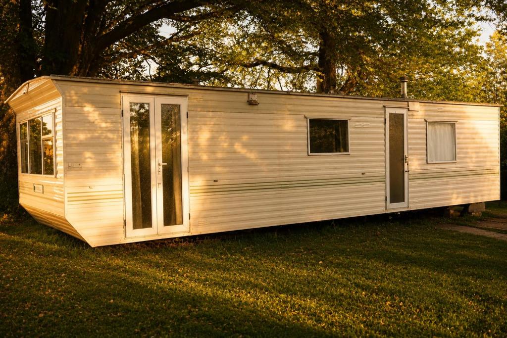 a white tiny house sitting in the grass at Chalet Ardennen The Great Hill in Amblève