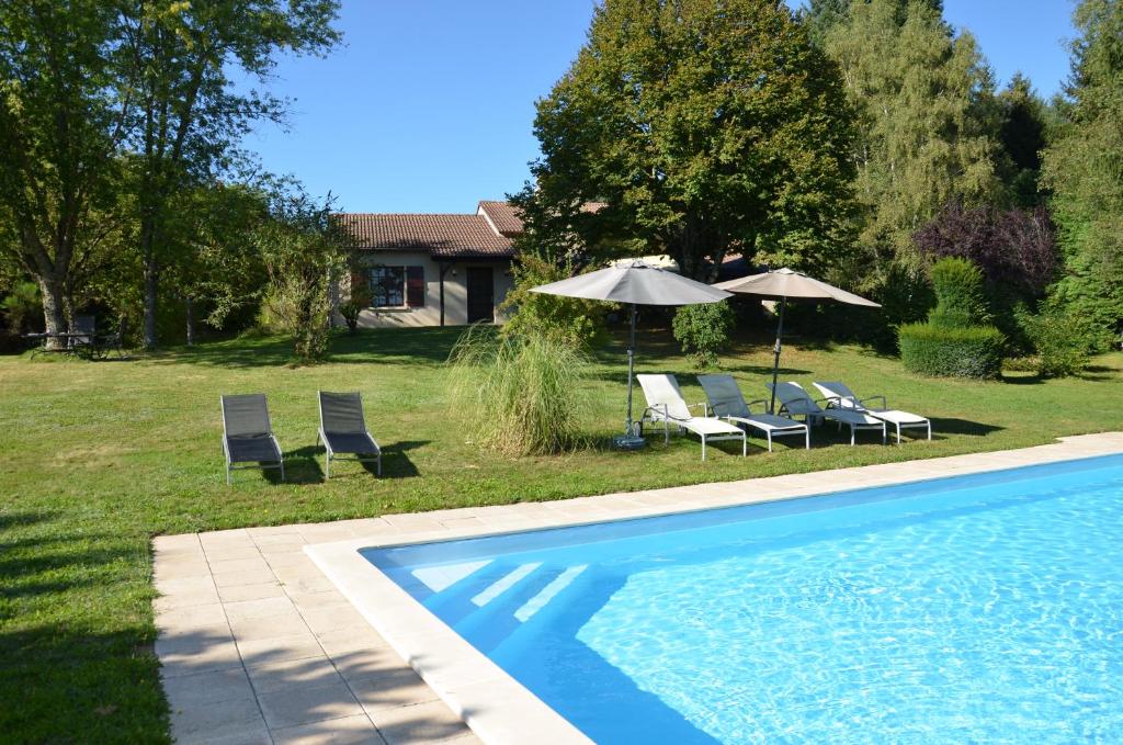 two chairs and umbrellas next to a swimming pool at Maison Lavande in Sousceyrac
