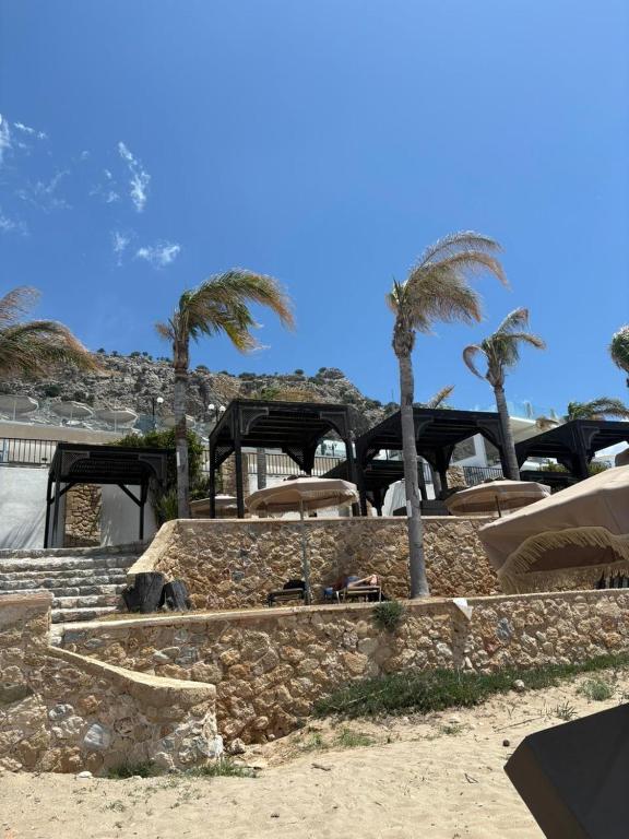 a resort with chairs and palm trees on the beach at Coralli Beachfront in Pefki
