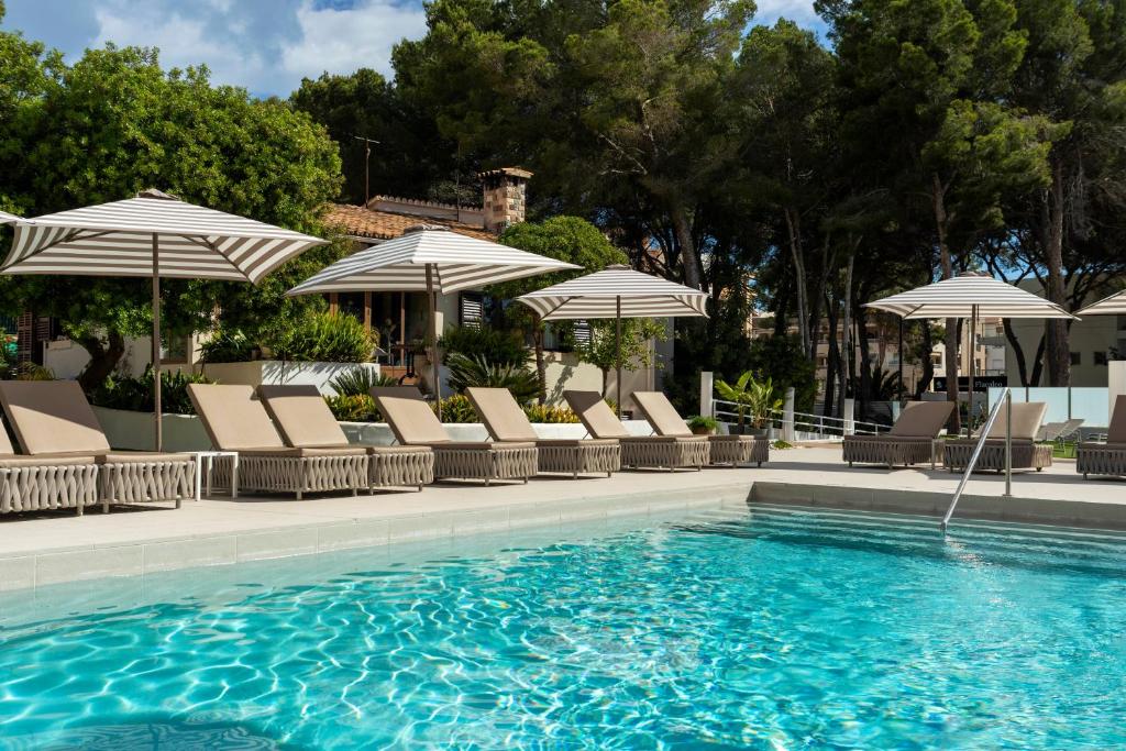 a swimming pool with chairs and umbrellas at Flacalco Hotel & Apartments in Cala Ratjada