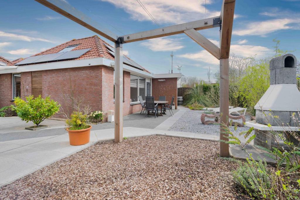 a backyard with a brick house with a pergola at Bungalowpark Herkingen 1B in Herkingen