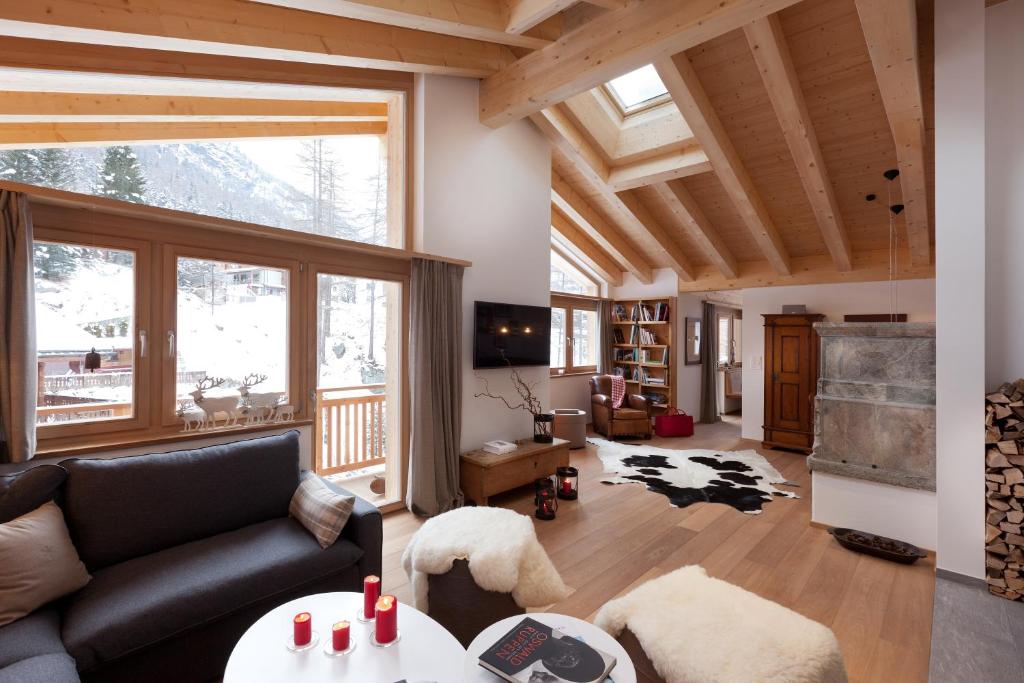 a living room with a couch and a large window at Chalet Banja in Zermatt