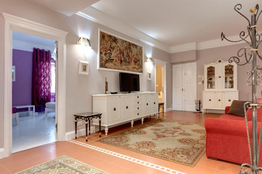 ein Wohnzimmer mit einem TV und einer roten Couch in der Unterkunft Florence Apartments, Home Feeling in Florenz
