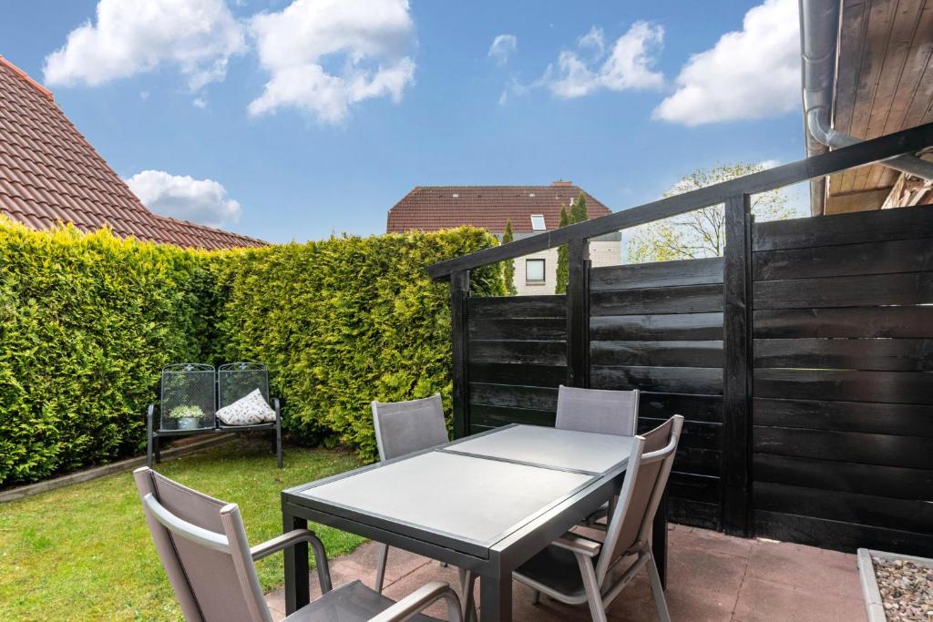 a table and chairs on a patio with a fence at Ferienwohnung Henrich in Hooksiel