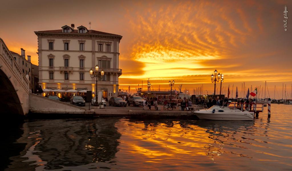 a building and a boat in the water at sunset at Hotel Grande Italia in Chioggia