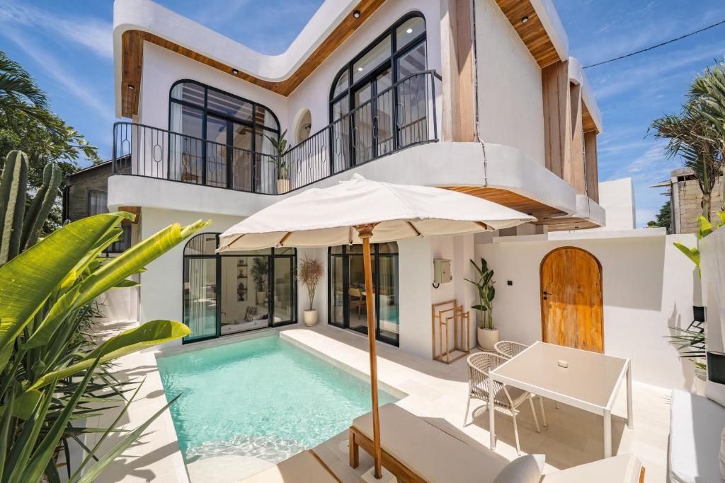 a house with a swimming pool and an umbrella at Villa Arco Pererenan in Canggu