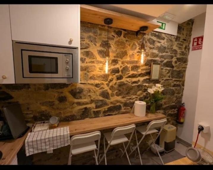 a kitchen with a stone wall with a table and chairs at Casa Magua Melide in Melide