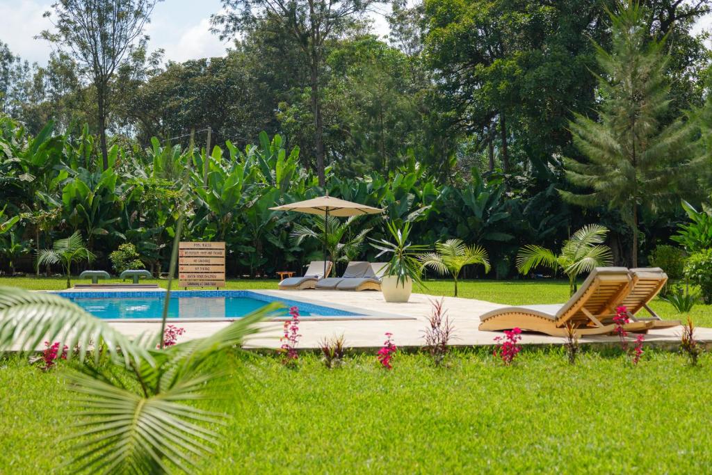 a pool with two lounge chairs and an umbrella at Tanzania Safari Lodge in Arusha