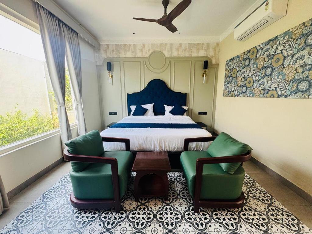 a bedroom with a bed and two green chairs at Hotel Lotus castle in Bathinda