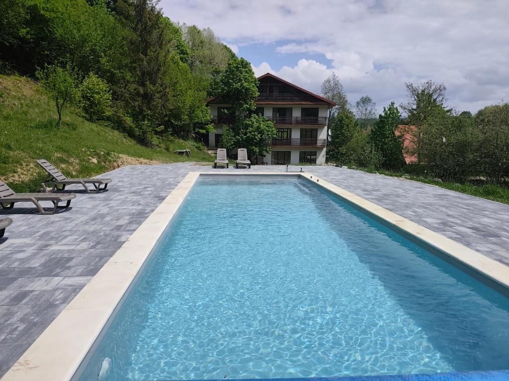 a swimming pool with two chairs and a house at Під Горбком in Bukovets