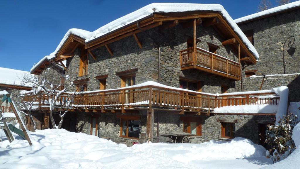 un grand bâtiment avec une terrasse dans la neige dans l'établissement Mon petit Chalet, à Valmeinier