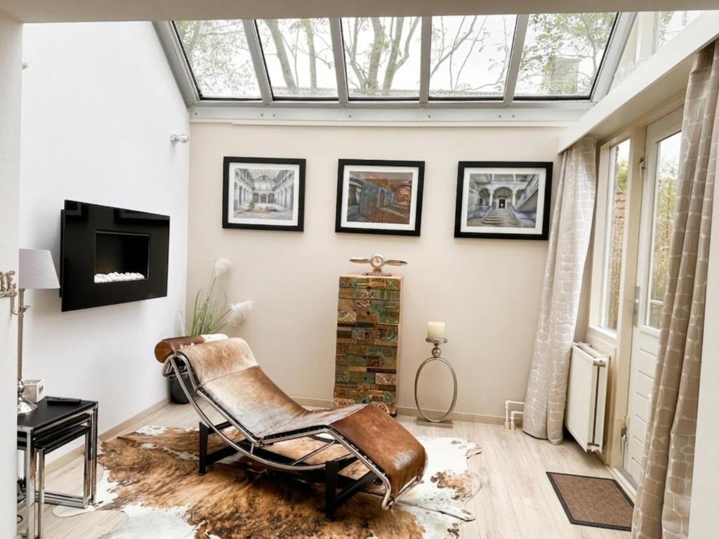 a living room with a skylight and a chair at Villa Relax Ooghduyne - Dünen Golf und Spa bei Beach & more in Julianadorp