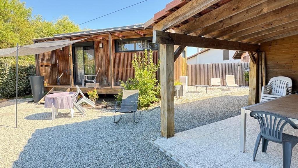 a patio with chairs and a table and an umbrella at EcoKub T3 Indépendant Proche plages et lac in Soustons