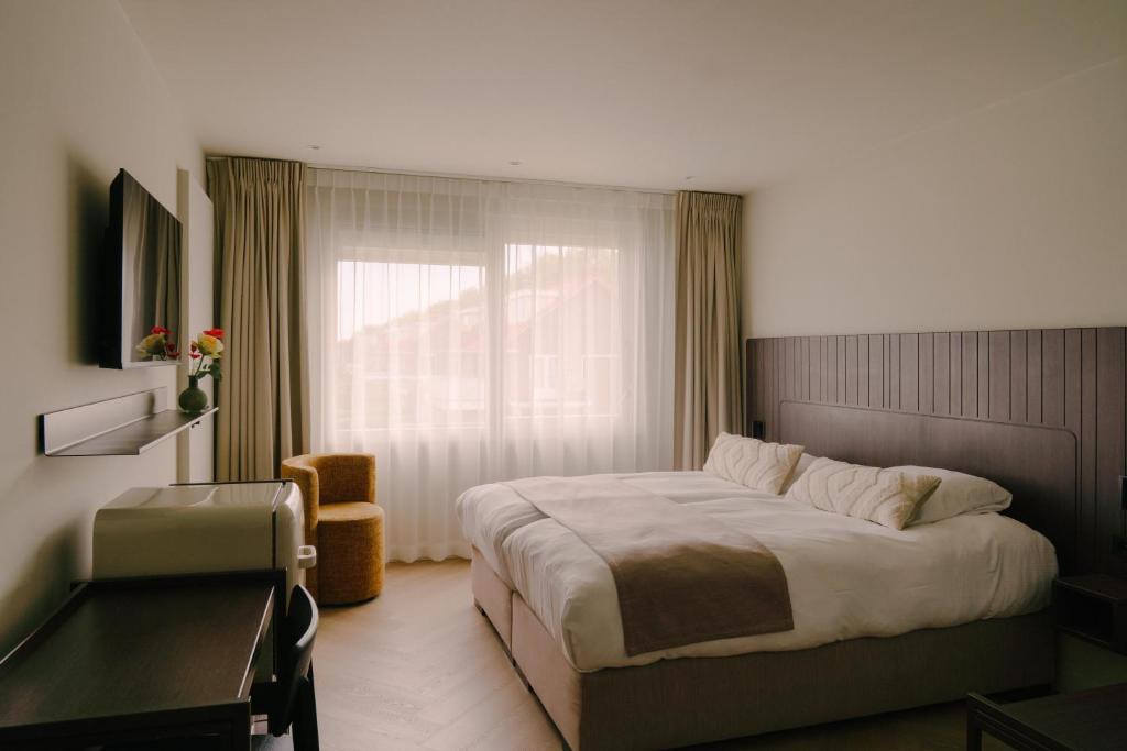 a bedroom with a bed and a desk and a window at Boutique Hotel Herbergh Amsterdam Airport FREE PARKING in Badhoevedorp