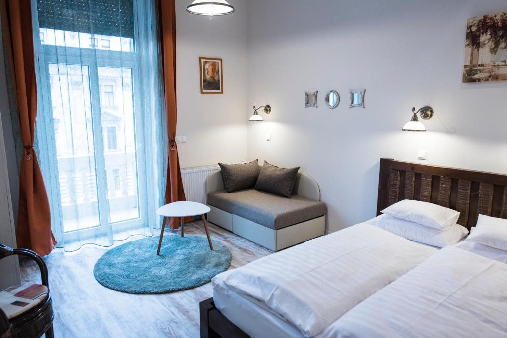 a bedroom with two beds and a chair and a window at All In Apartman III. in Budapest