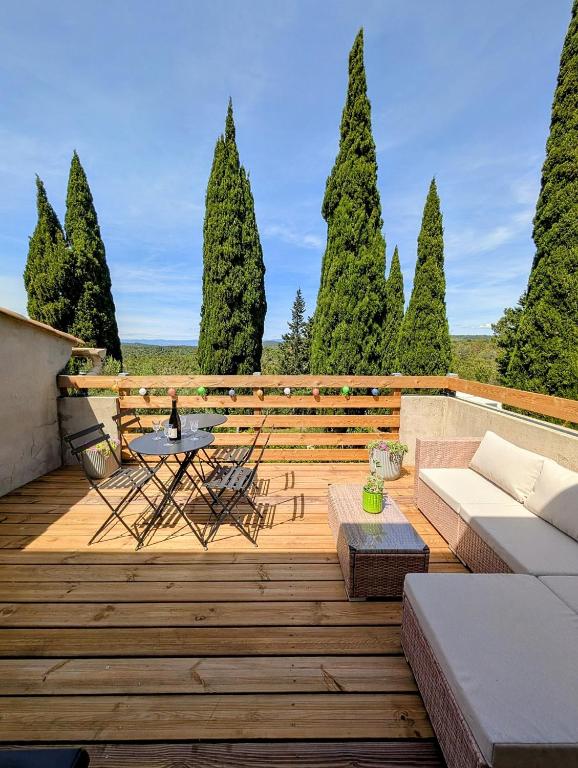 a wooden deck with a table and chairs and trees at L'Ecrin de Pommayrac - Appartement Nature, au coeur d'un centre équestre in Verzeille
