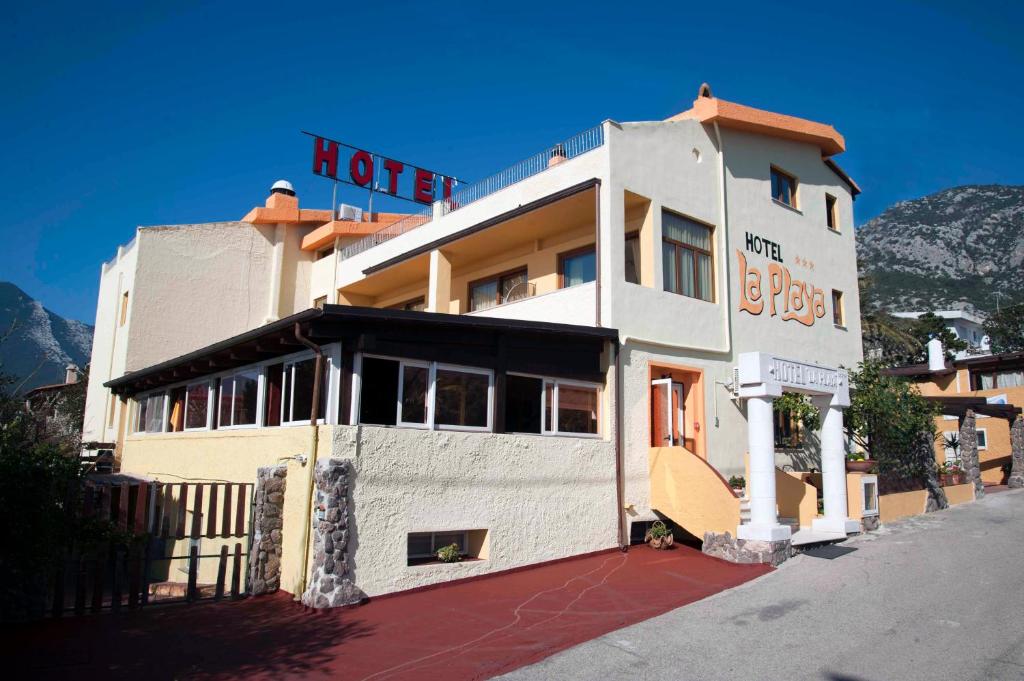 a hotel building with a sign on top of it at Hotel La Playa in Cala Gonone