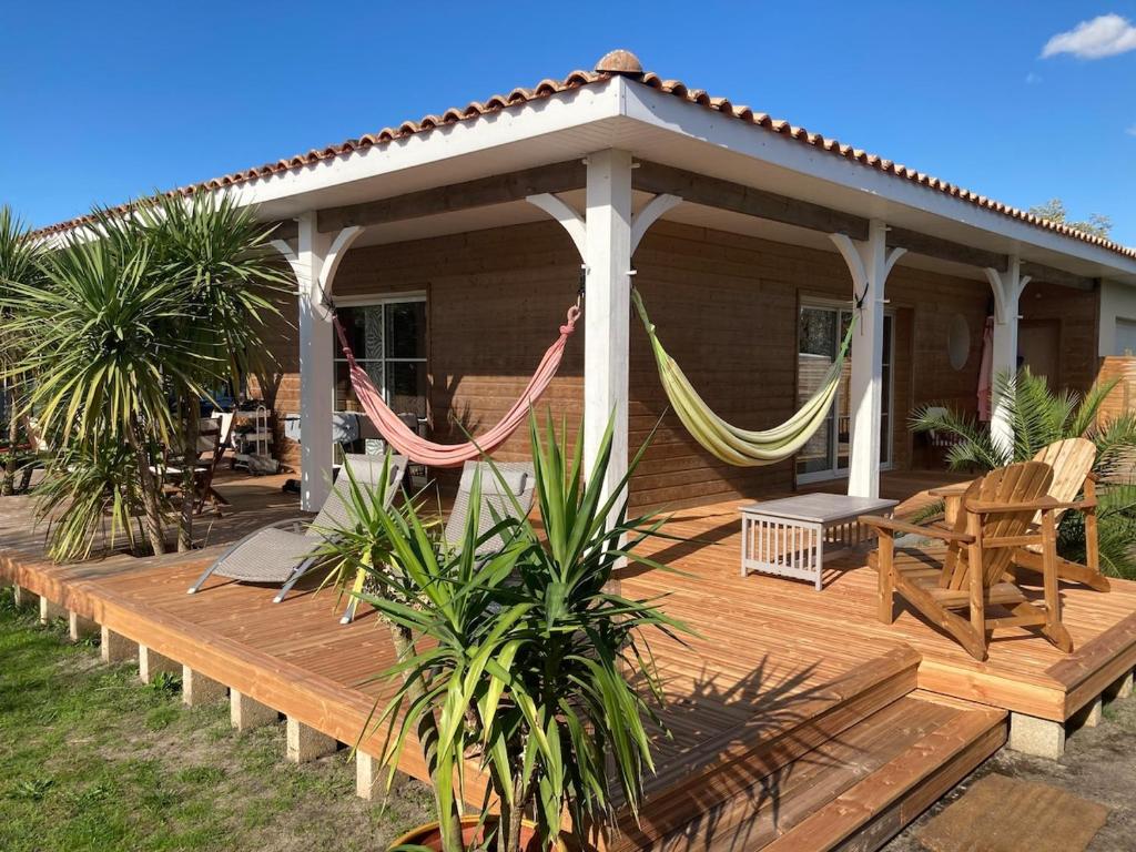 a wooden deck with a gazebo and hammocks at Villa ALoha in Carcans