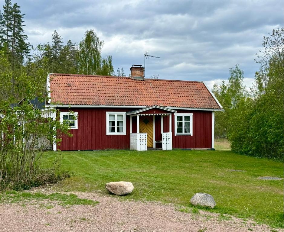 a red house with a red roof on a yard at Ytterbo in Hultsfred