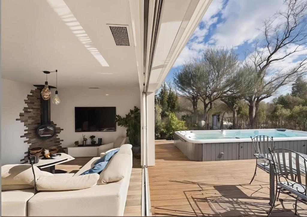 a living room with a white couch and a swimming pool at Villa Émeraude Spa in Le Porge