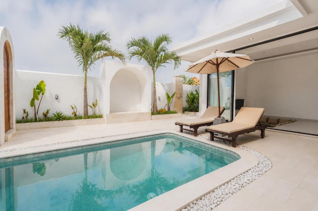 a swimming pool with two chairs and an umbrella at Ruana Villa Pererenan in Munggu