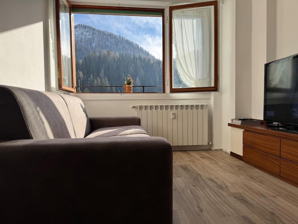 a living room with a couch and a large window at Foppolo GH in Foppolo