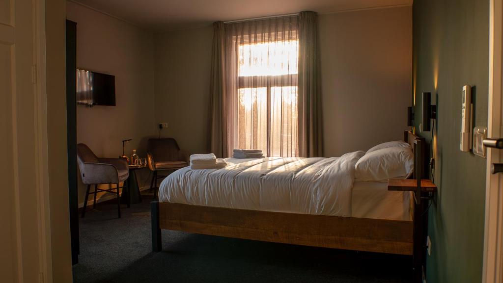 a bedroom with a bed and a window at Restaurant & Hotel De Jaeger in Ruurlo