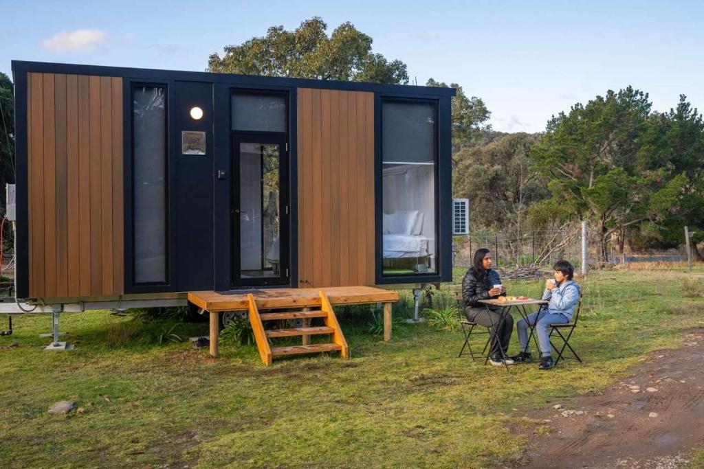 two people sitting at a table in front of a tiny house at Sparkling Tiny House by Tiny Away in Windeyer