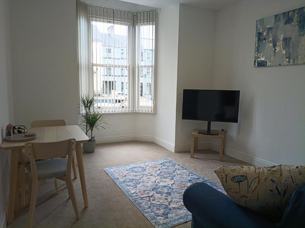 a living room with a table and a tv at The Loy Guest Apartment in Cookstown