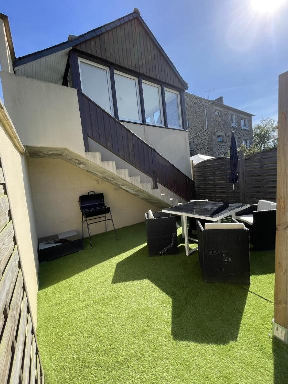 a house with a lawn with a table and chairs at Le Carré Vert, appartement avec terrasse in Lamballe Armor