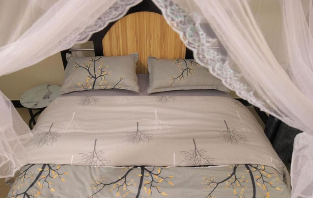 a bed with a canopy and pillows with curtains at Atié Haven in Lira