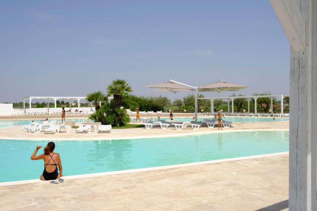a woman in a bikini walking by a swimming pool at Basilicata Host to Host - Le Muse in Stazione di Metaponto