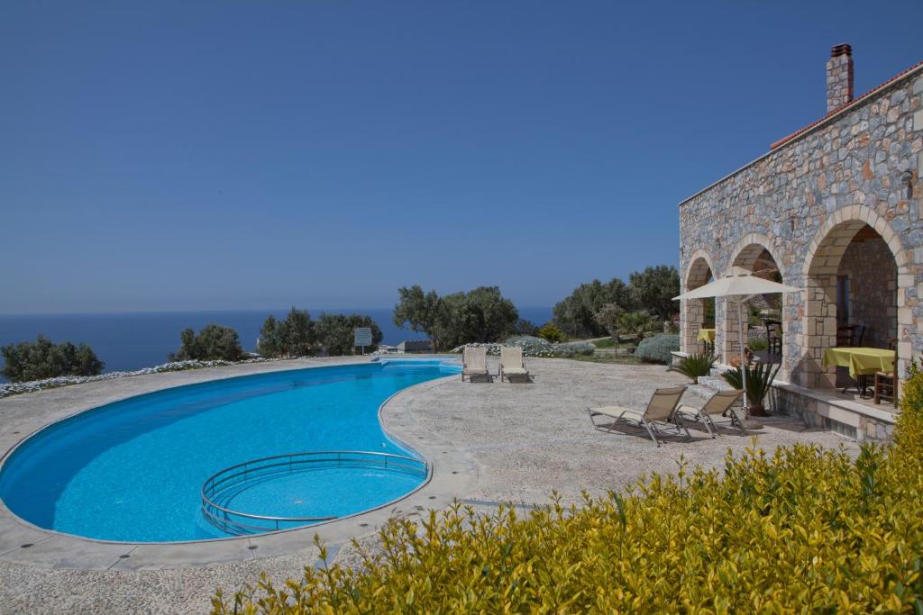 una piscina junto a un edificio de piedra con un complejo en Pegasus Resort, en Agia Paraskevi