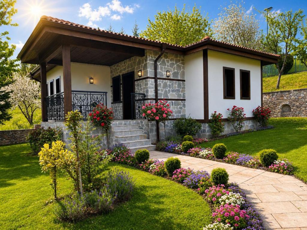 a small white house with flowers in front of it at Бутиков хотел "Родопски Легенди" in Vrata