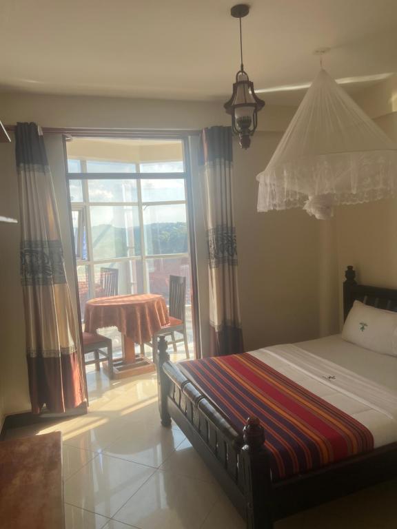 a bedroom with a bed and a table and a window at Acactus Hotel in Kampala