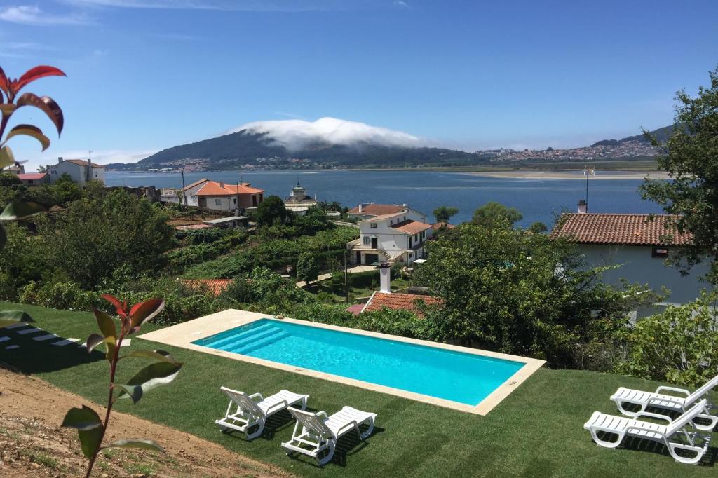 a swimming pool with lawn chairs and a mountain at aMaRe Country House in Caminha