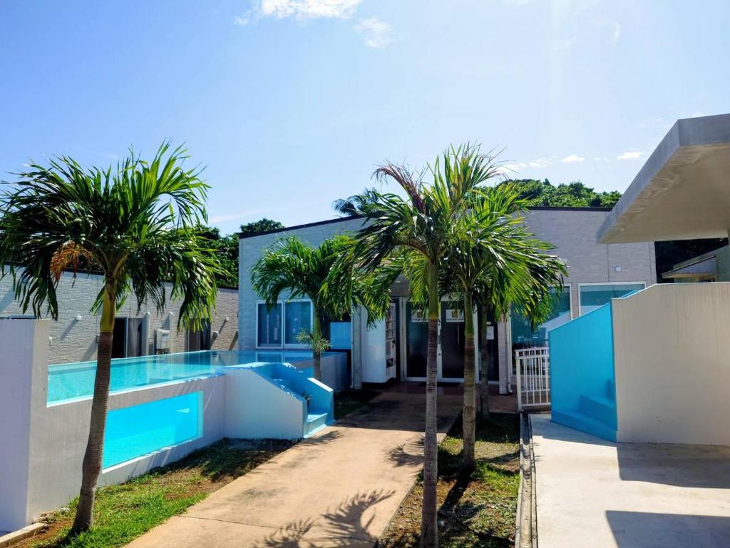 a house with a swimming pool and palm trees at Rich Reson Ishigaki in Ishigaki Island