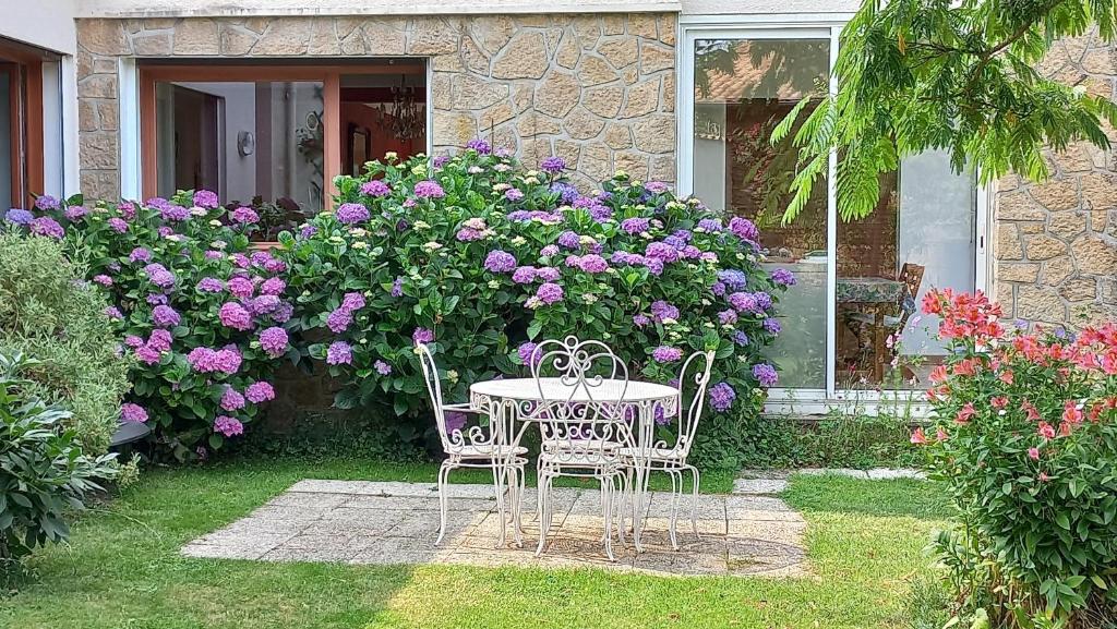 a table and chairs in a yard with flowers at Chambres hôtes Le Champ Des Oiseaux in Rochechouart