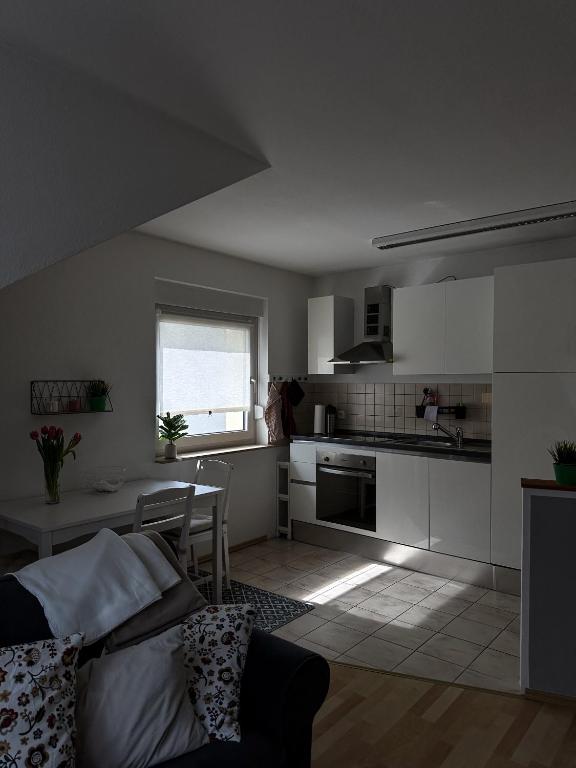 a kitchen with white cabinets and a couch in a room at Gemütlich unterm Dach in Baunatal
