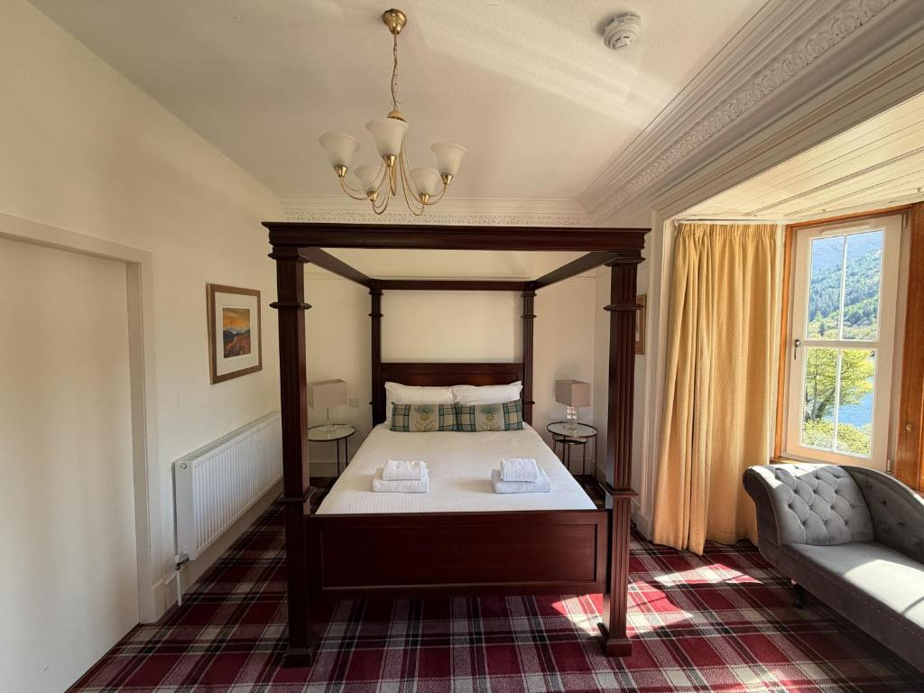 a bedroom with a canopy bed and a couch at Loch Leven Hotel & Distillery in Glencoe