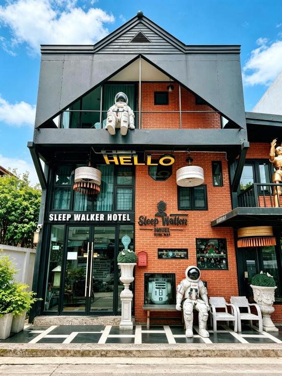 a building with two people sitting on a bench in front at Sleep Walker Poshtel in Chiang Mai