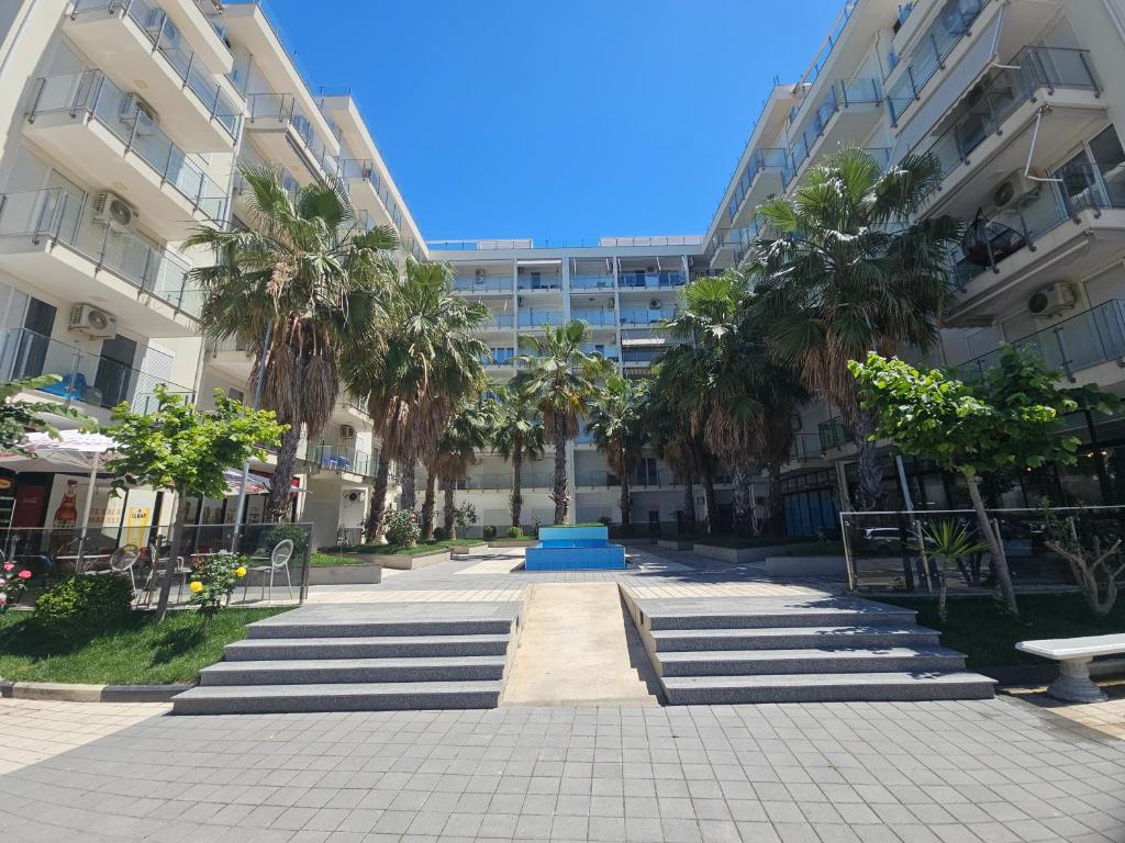 a courtyard in front of a building with palm trees at Sea&Stay in Shëngjin