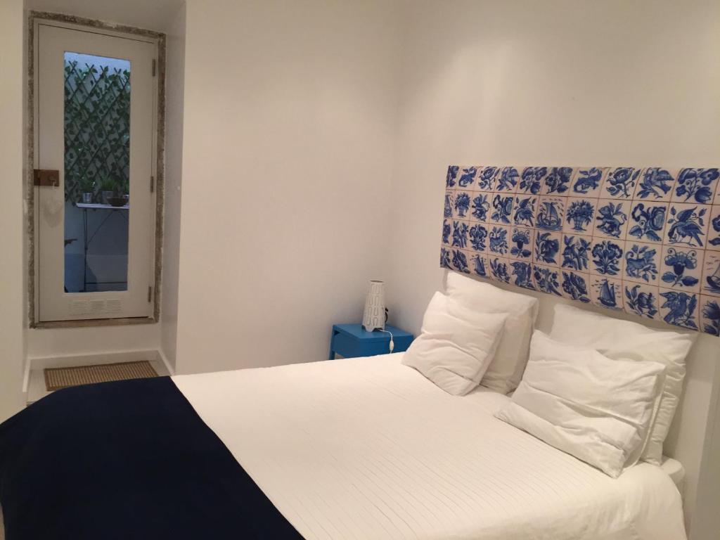 リスボンにあるBairro Alto 27のベッドルーム1室(白と青のヘッドボード付きの白いベッド1台付)